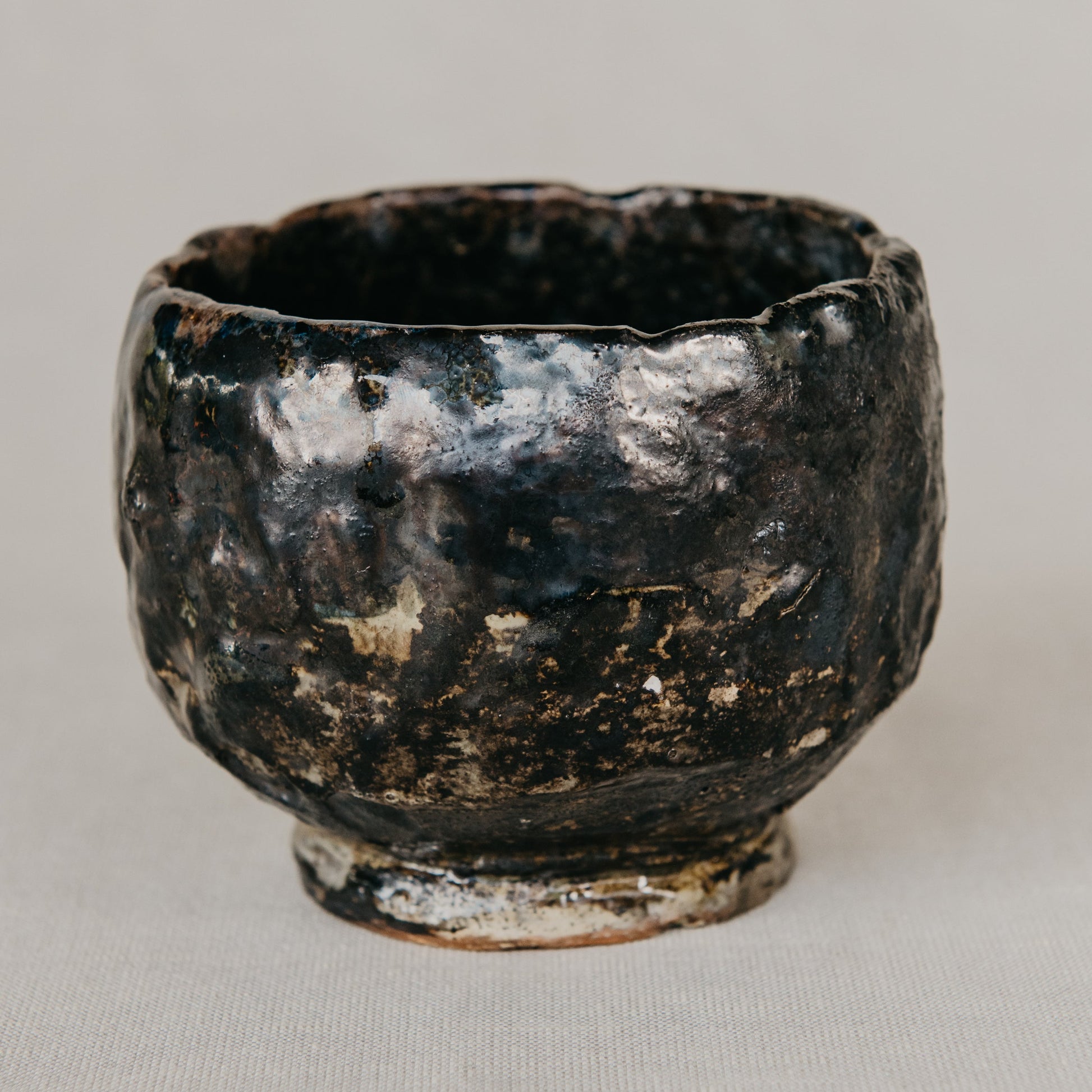 Black ceramic cup with a textured surface on a light gray background