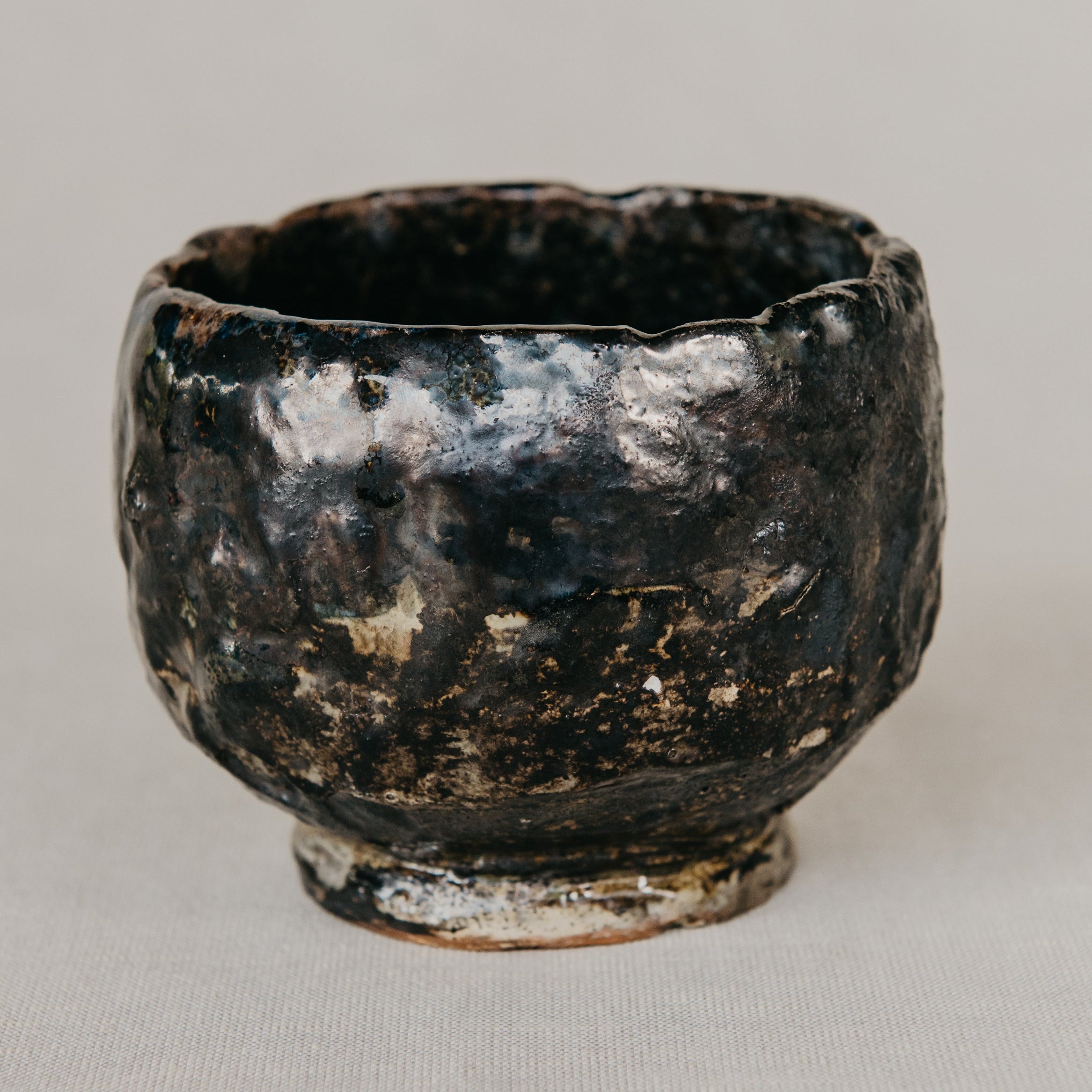Black ceramic cup with a textured surface on a light gray background
