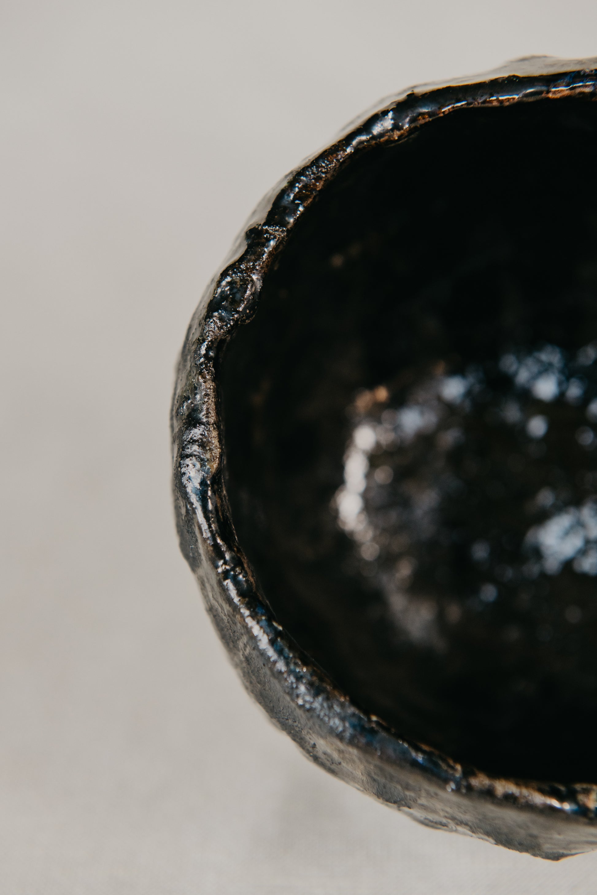 Close-up of a black ceramic bowl with a textured surface on a light gray background