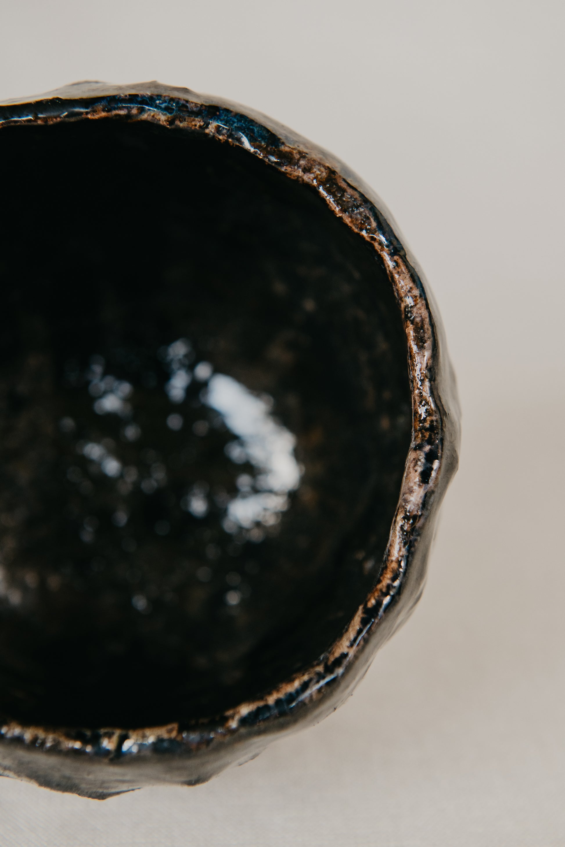 Close-up of a dark ceramic bowl with a textured surface on a light background