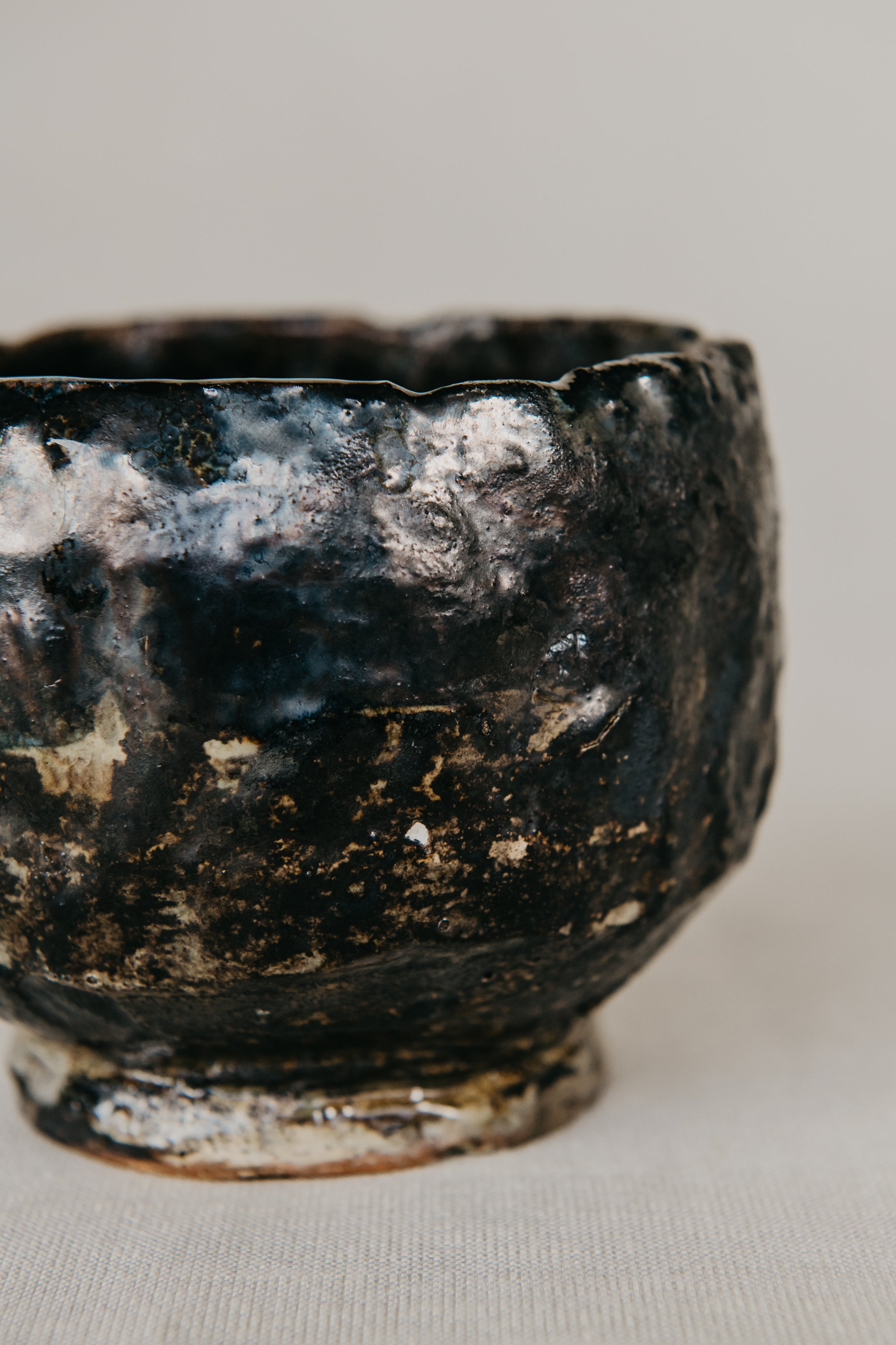 Black ceramic bowl with a textured surface on a neutral background