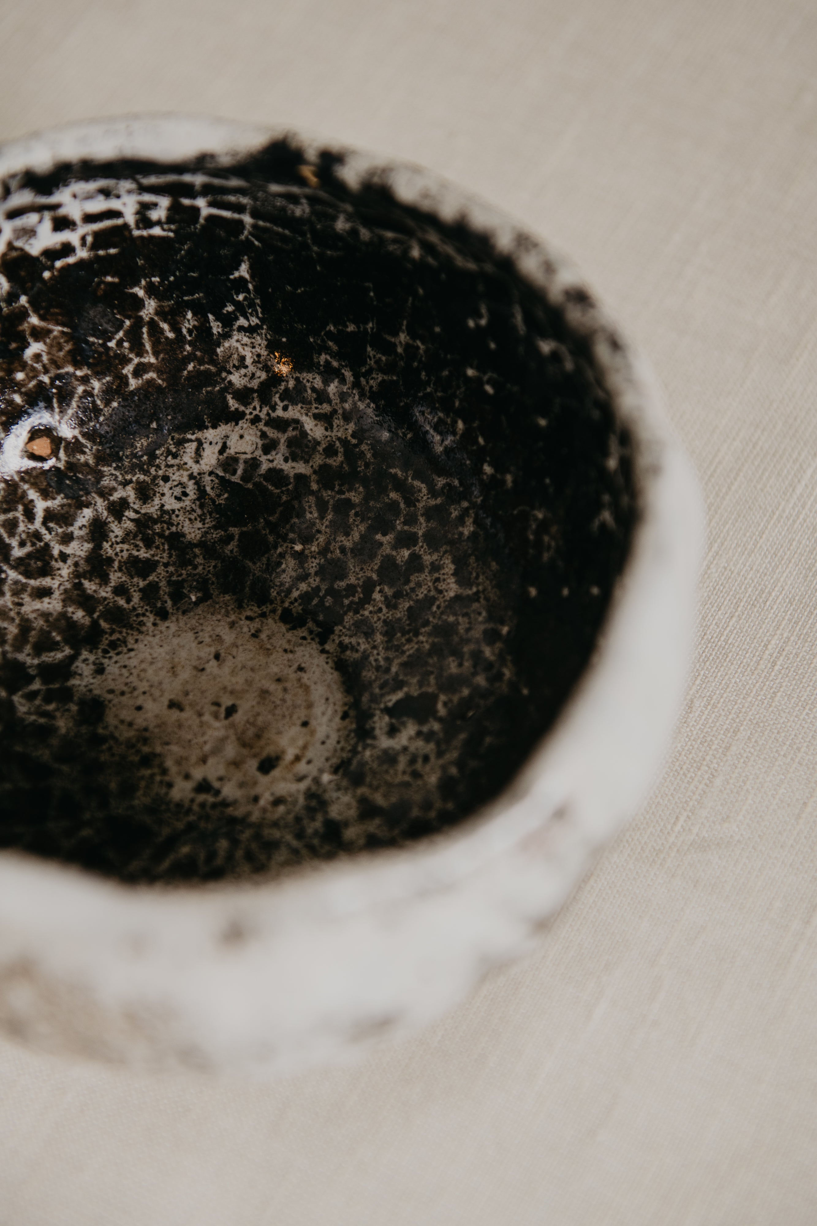 Close-up of a textured ceramic bowl with a speckled pattern on a beige background