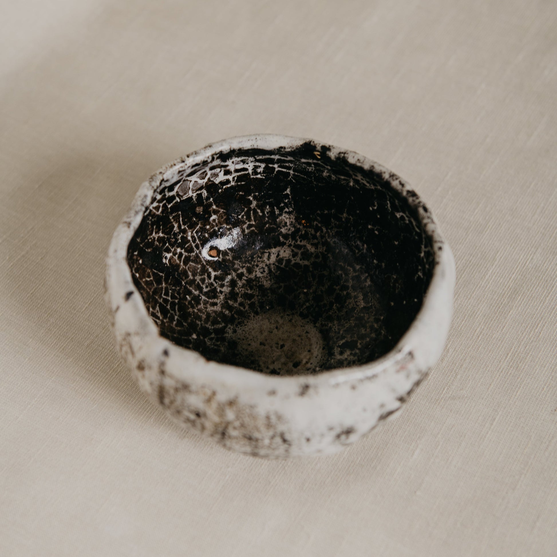 Ceramic bowl with textured surface on a beige fabric background