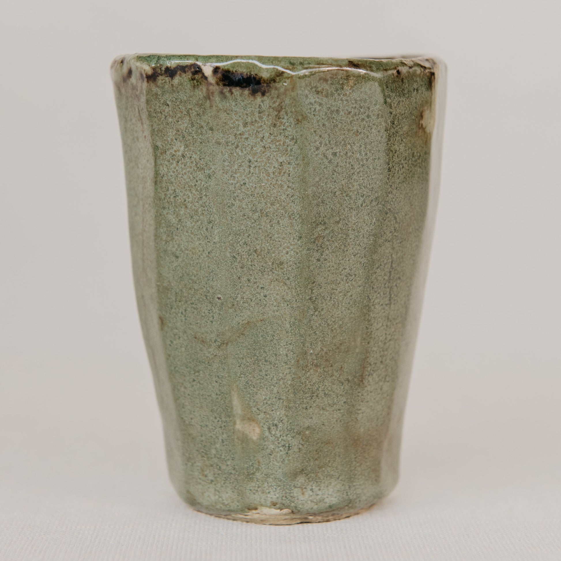 Green ceramic cup with textured surface on a white background