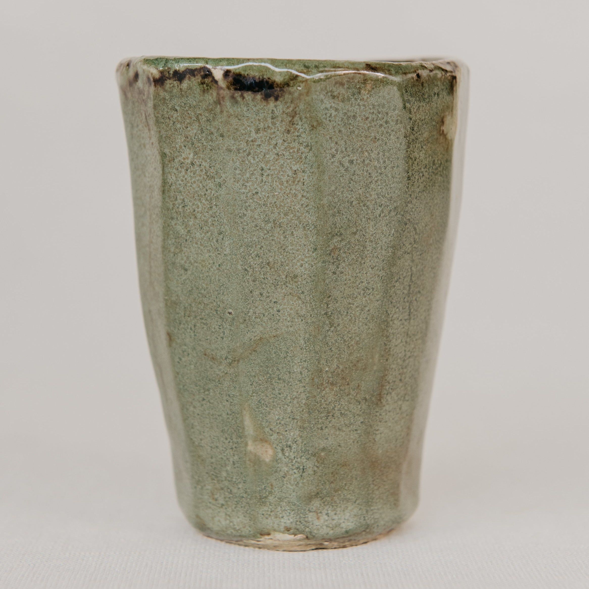 Green ceramic cup with textured surface on a white background