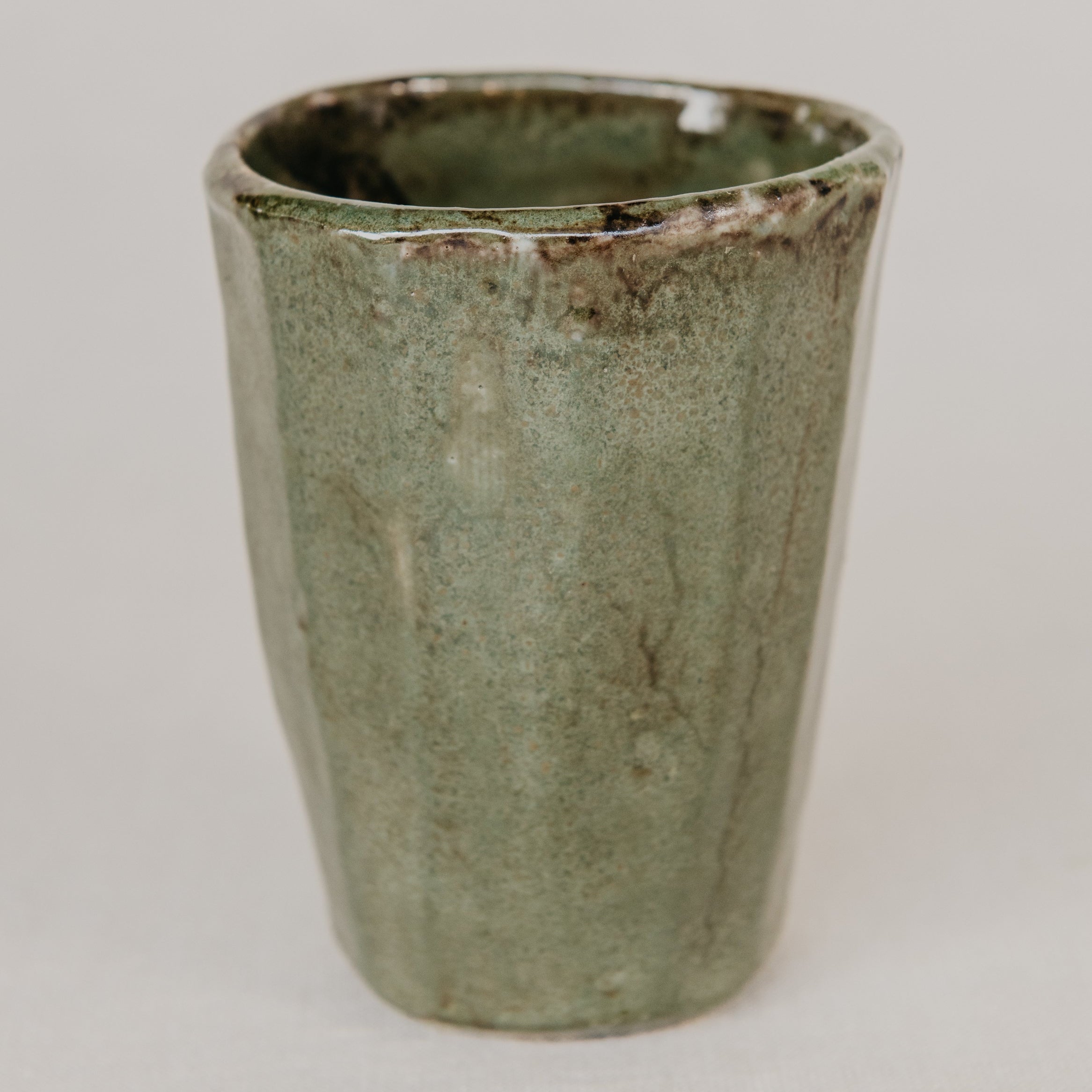 Green ceramic cup on a light gray background