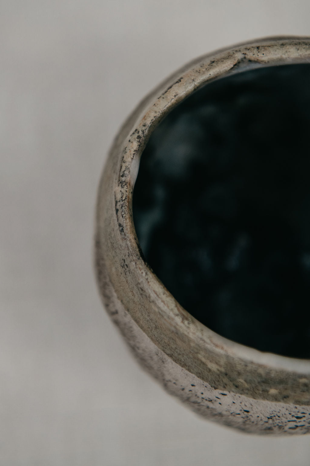 Close-up of a textured ceramic bowl with a dark interior on a neutral background
