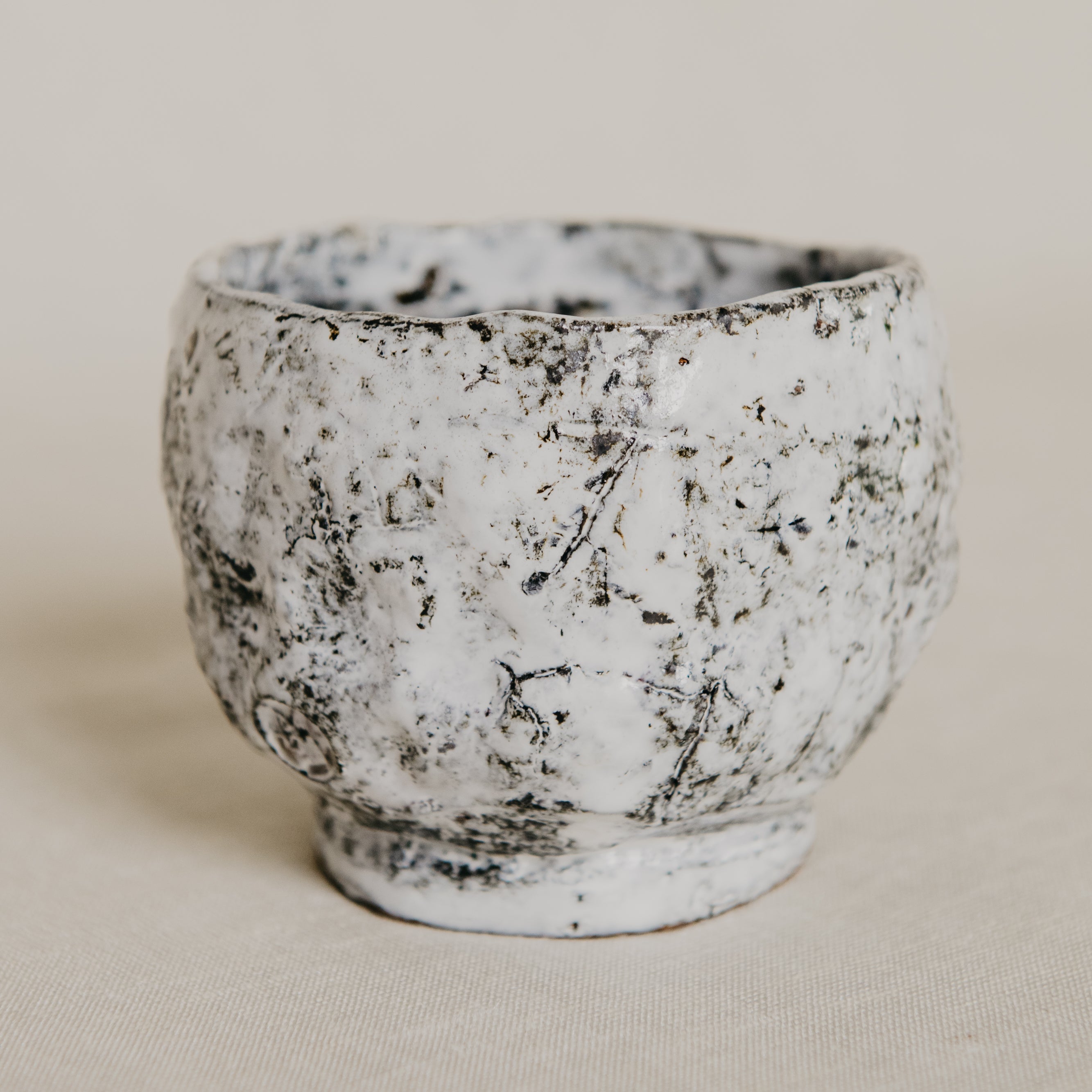 Small ceramic cup with textured surface on a beige background