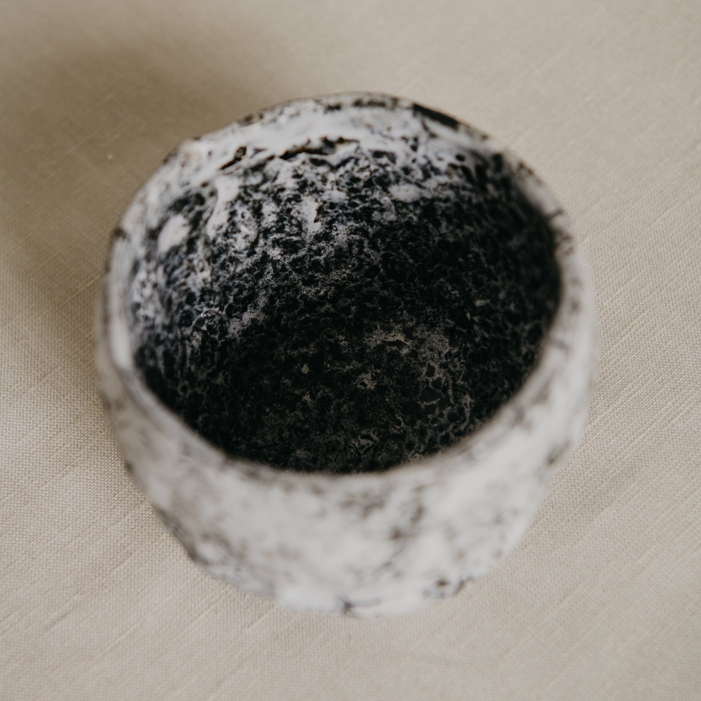 Round black object with a textured surface on a beige fabric background