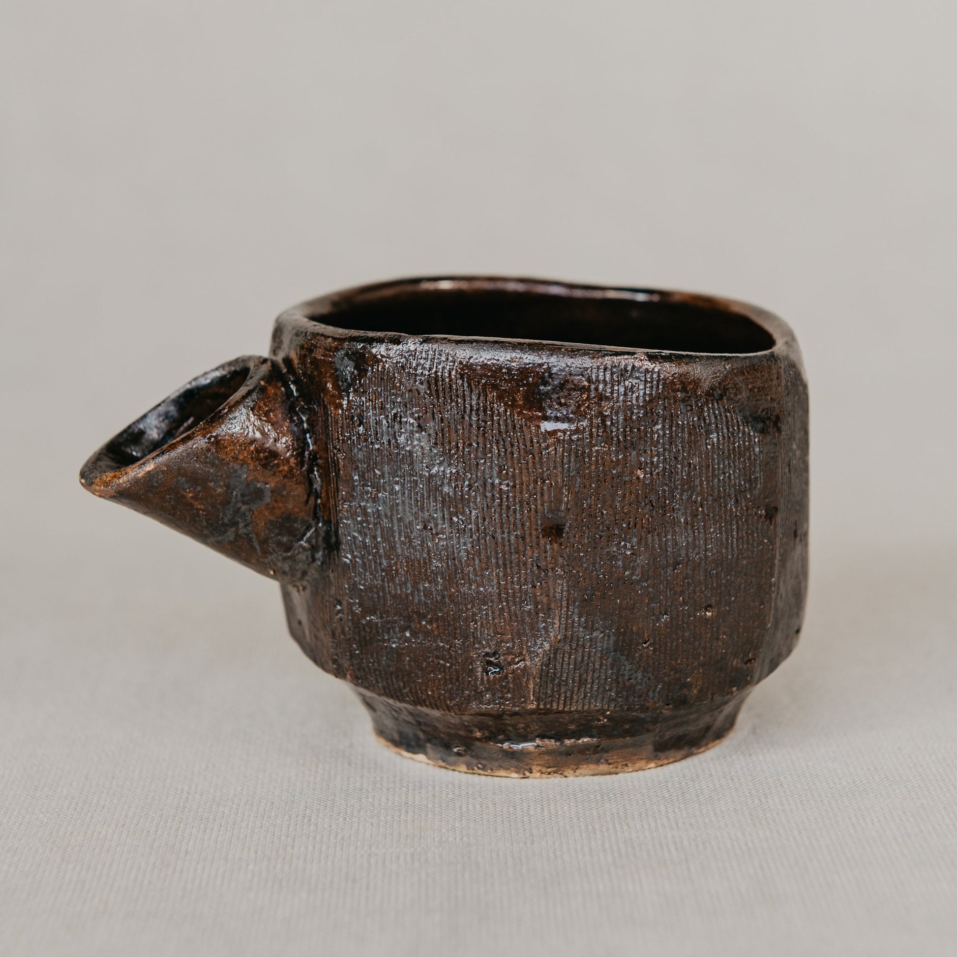 Brown ceramic cup with handle on a light gray background