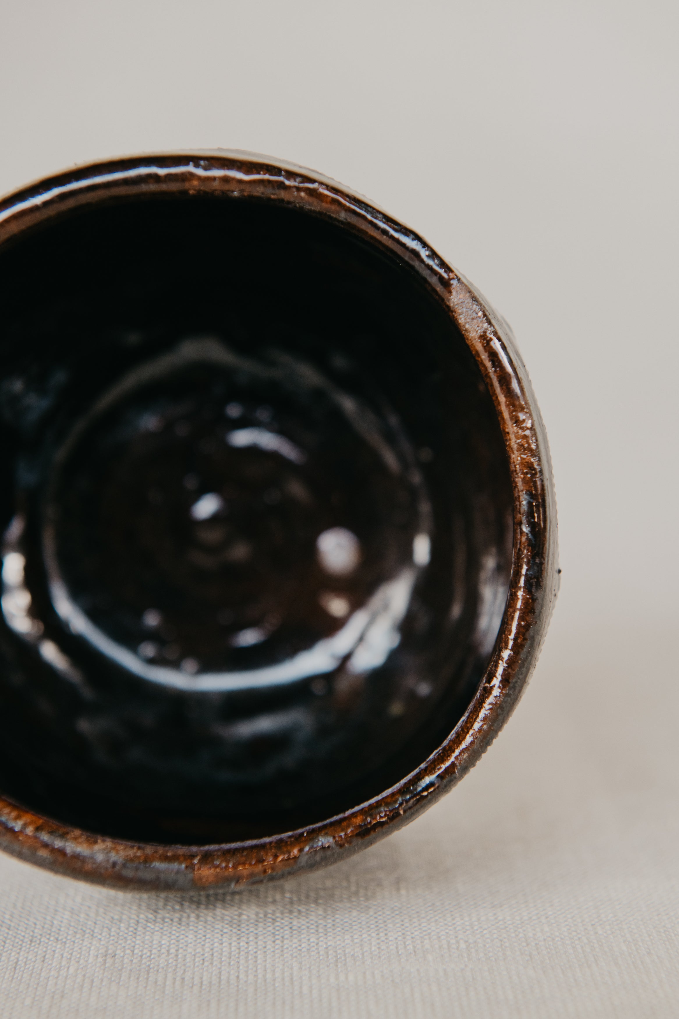 Close-up of a dark brown ceramic cup on a light background
