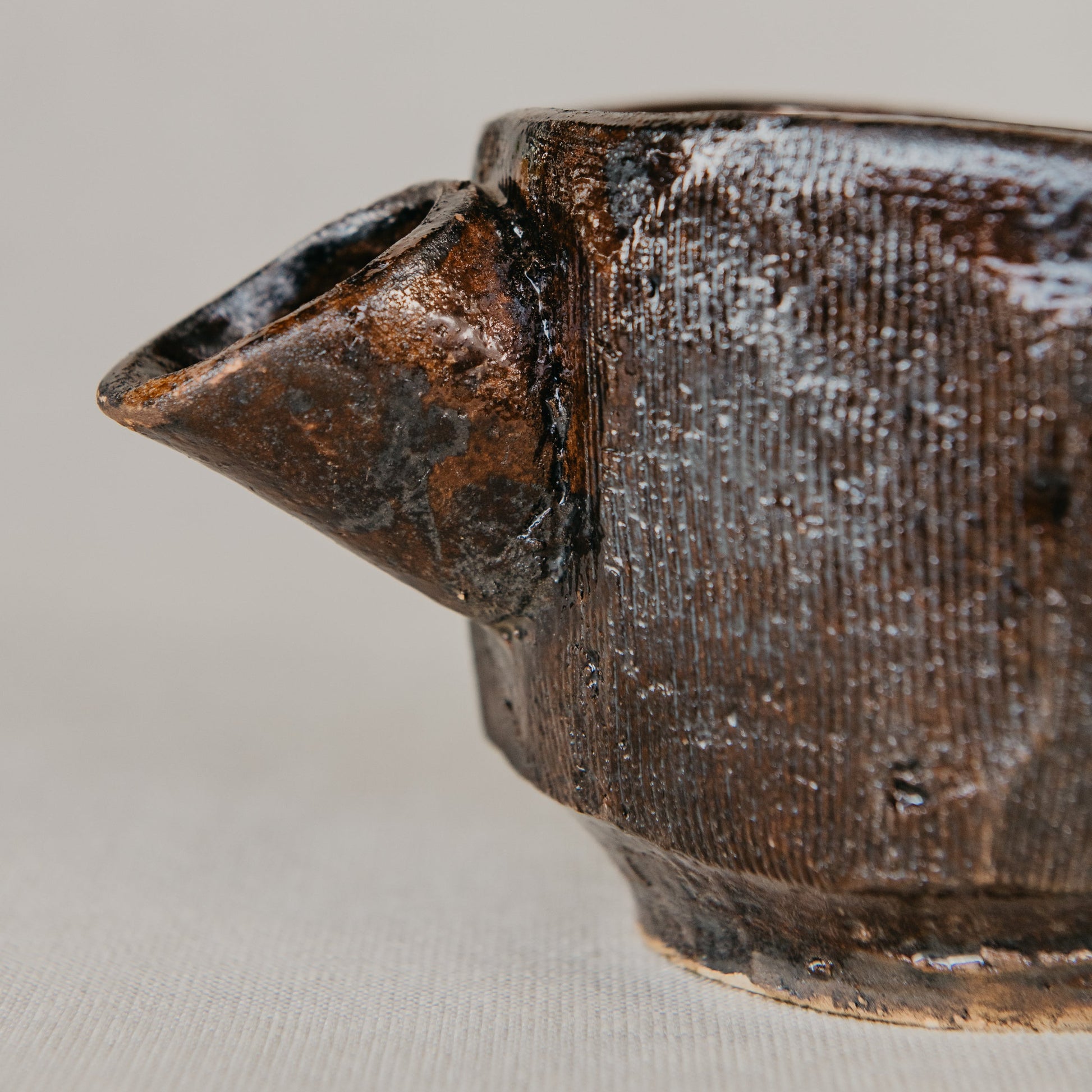 Close-up of a ceramic teapot with a textured surface on a light gray background