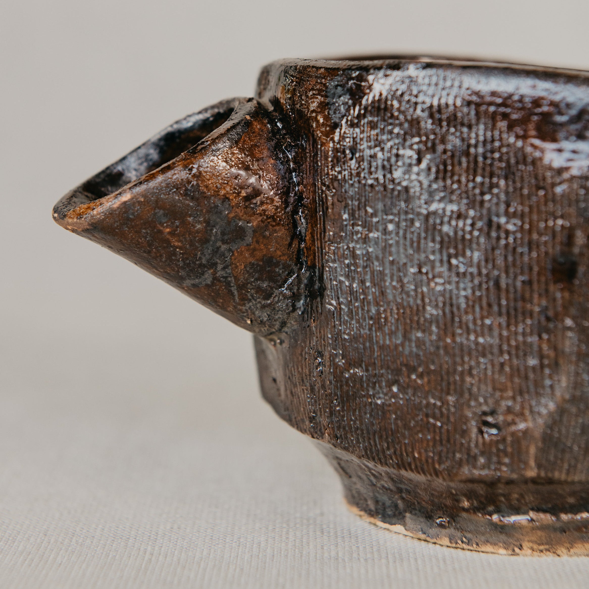 Close-up of a ceramic teapot with a textured surface on a light gray background