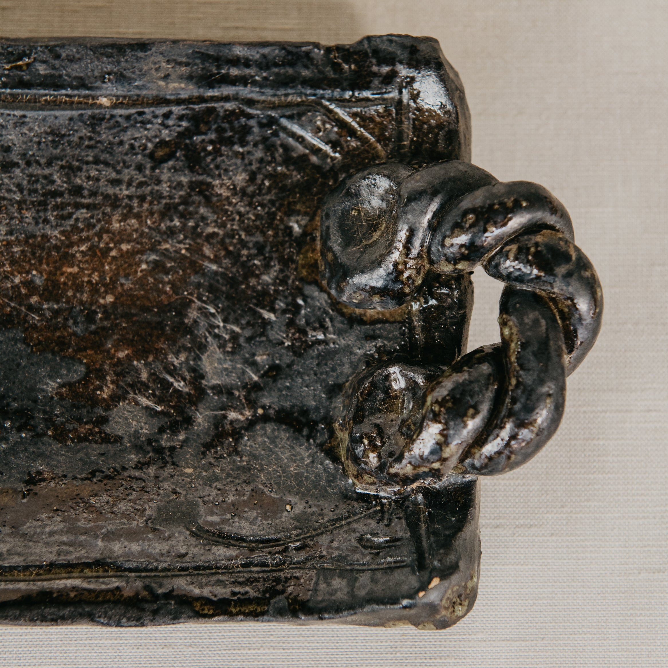 Decorative metal object with a knotted handle on a neutral background