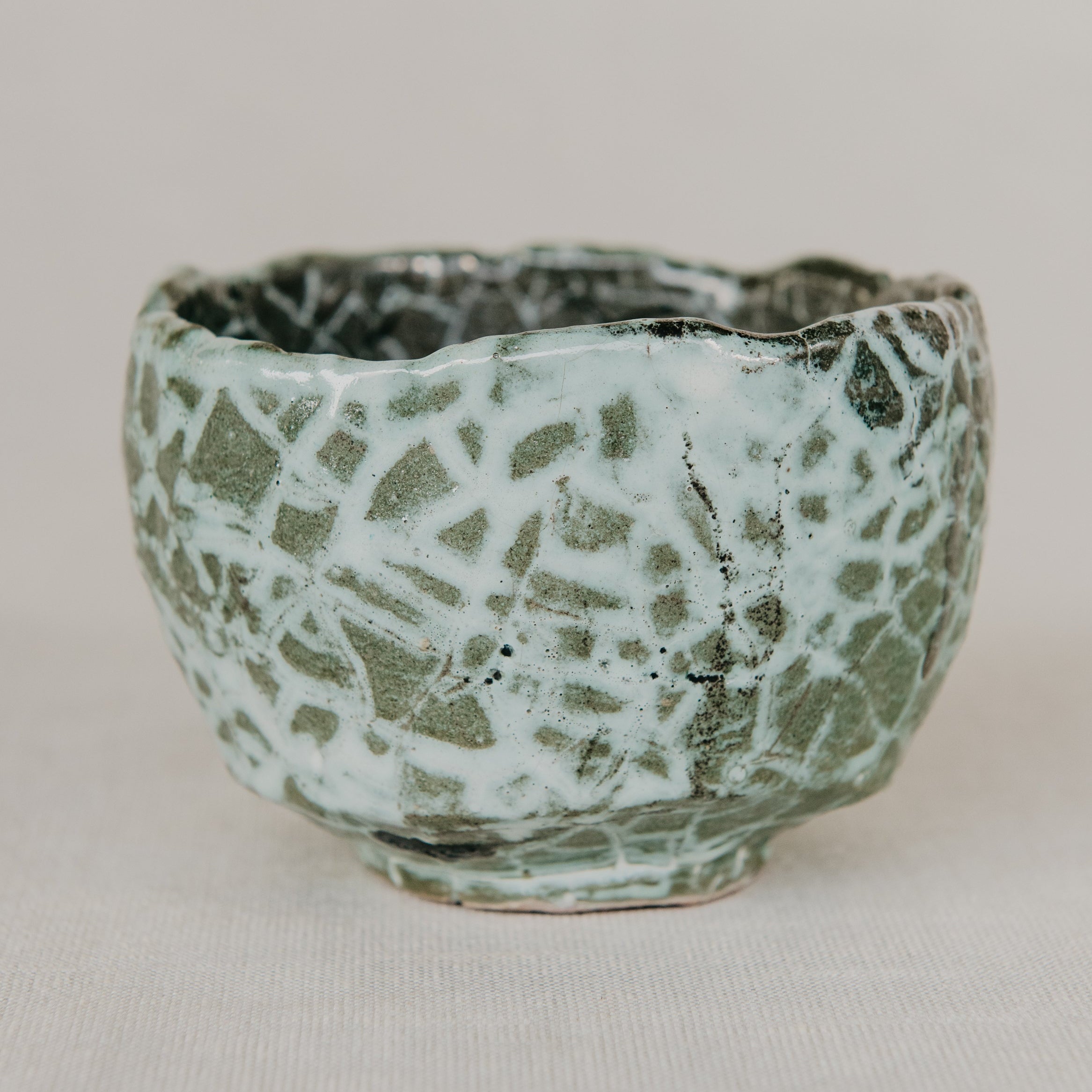 Small ceramic cup with textured surface on a plain background