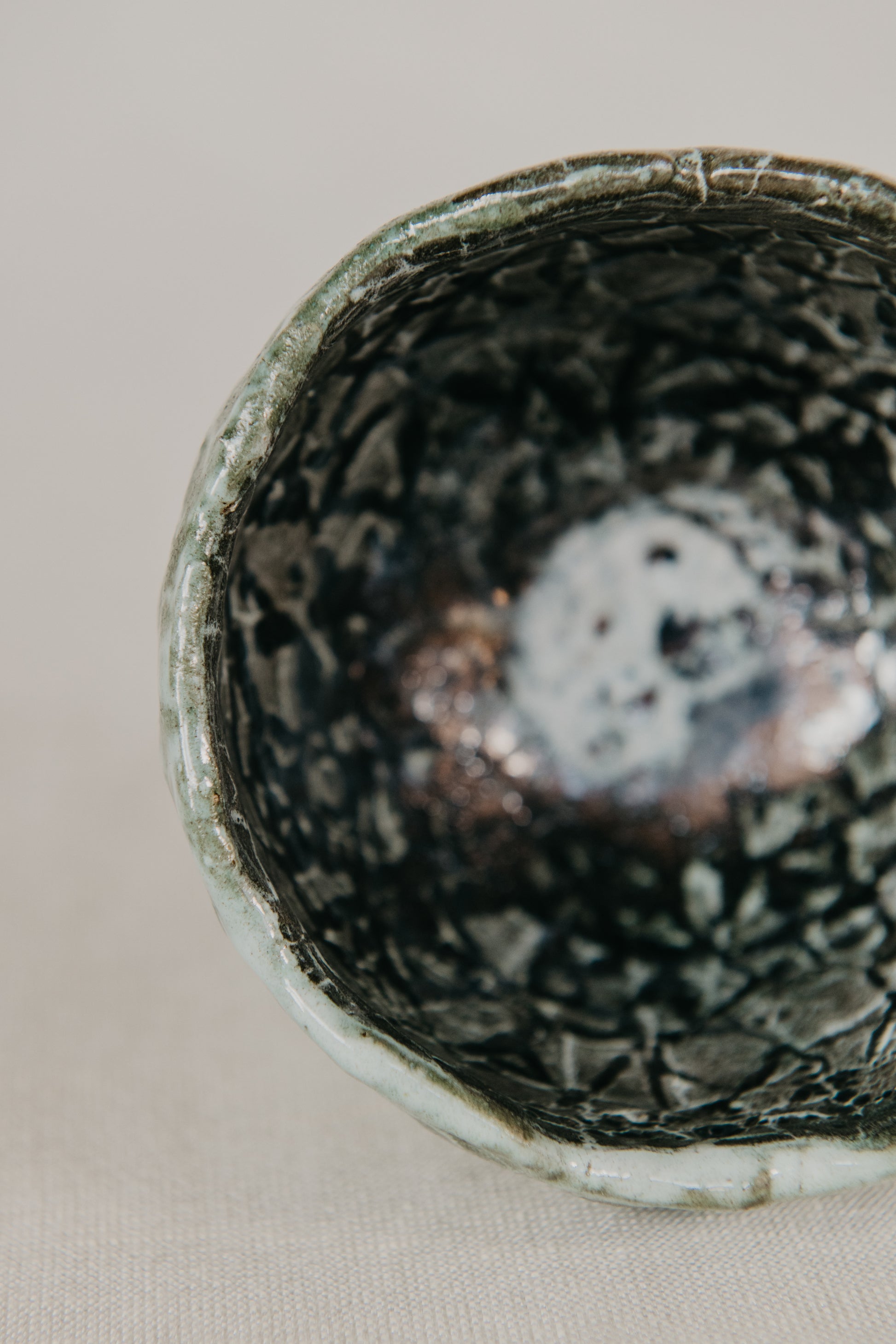 Close-up of a textured ceramic bowl with a speckled pattern on a neutral background