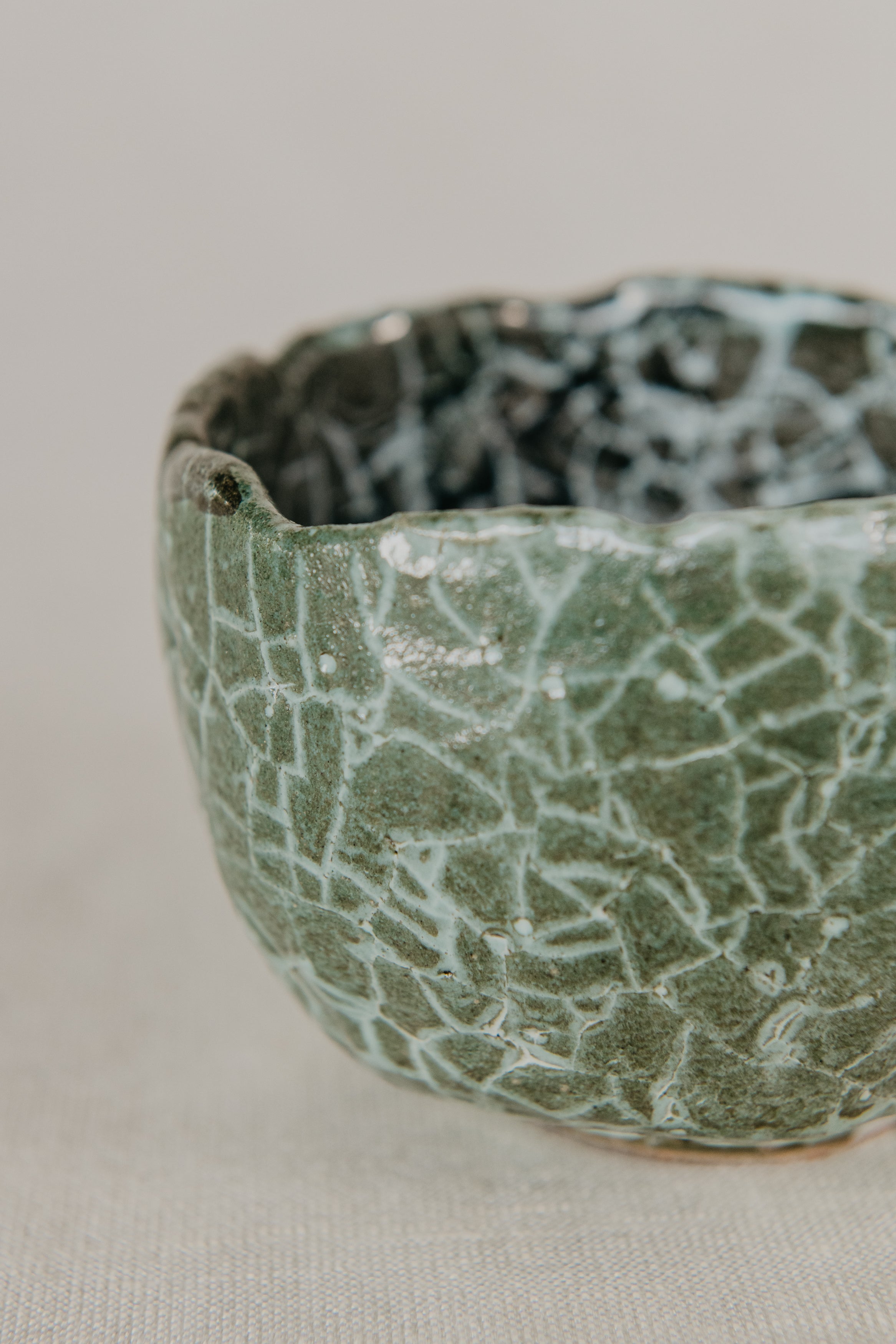 Green ceramic bowl with textured surface on a light gray background