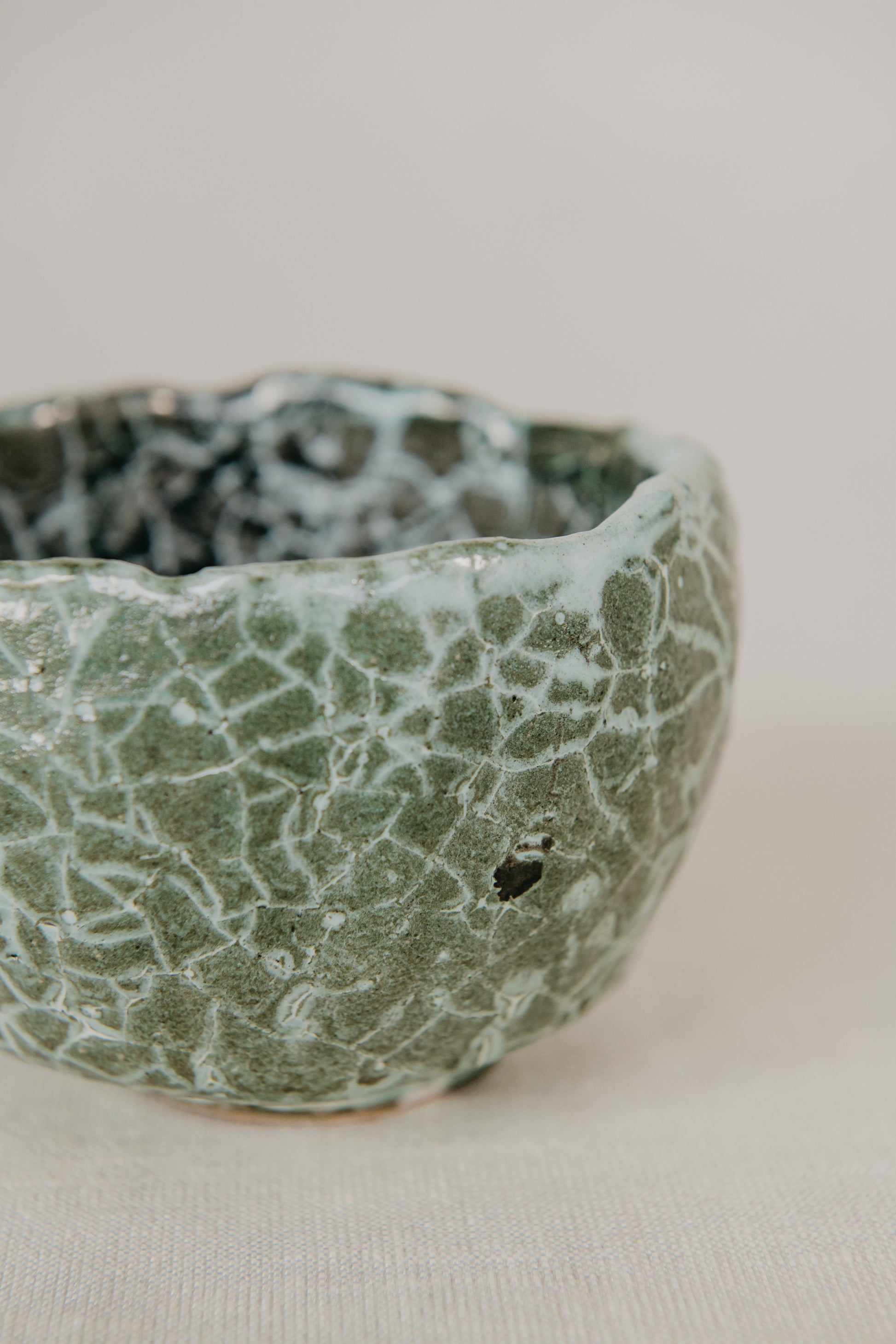 Ceramic bowl with textured green and white surface on a plain background