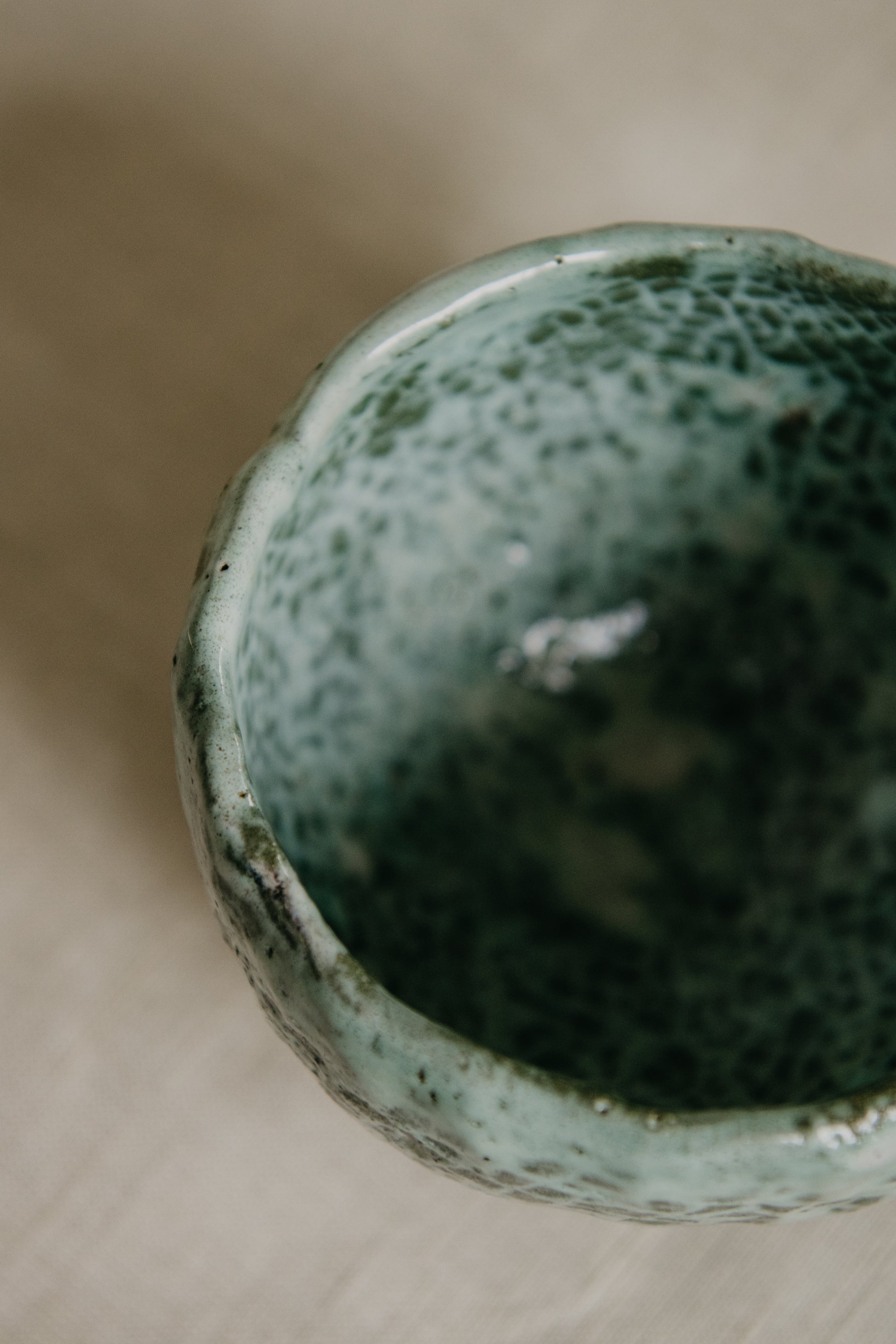Green ceramic pot with textured surface on a wooden surface