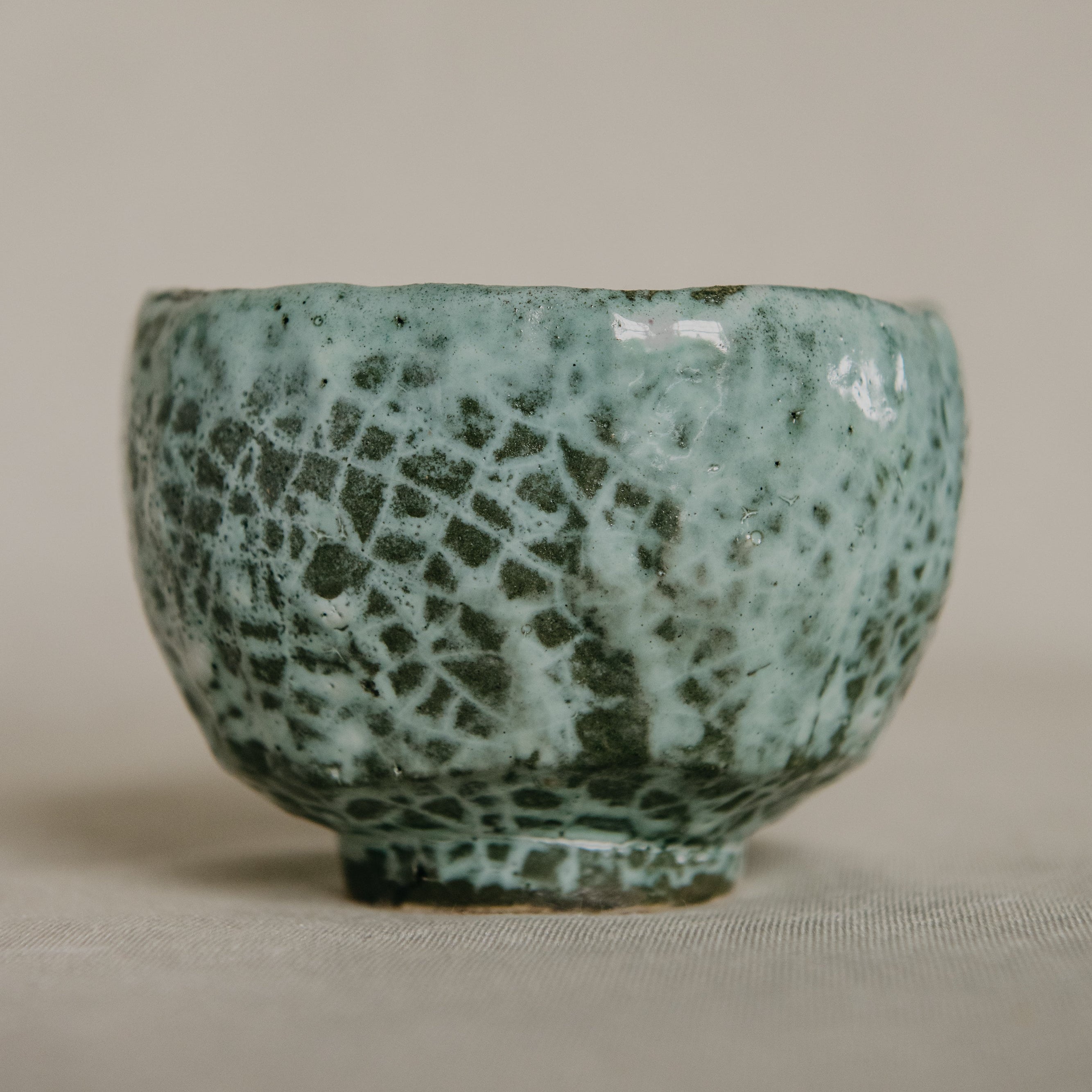 Green ceramic bowl with textured surface on a beige background