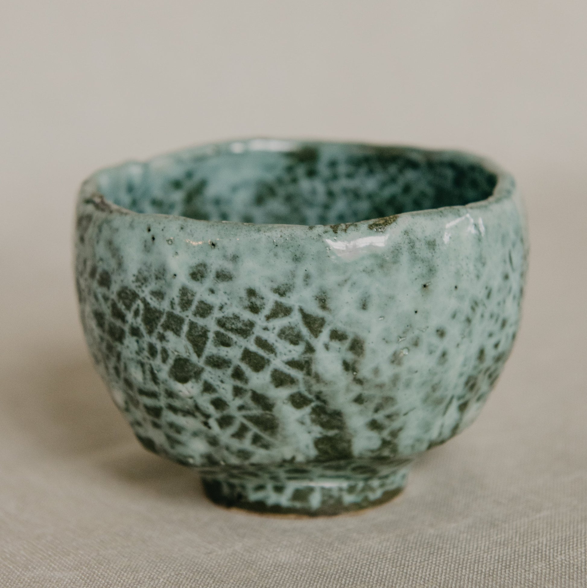 Green ceramic bowl with textured surface on a beige background