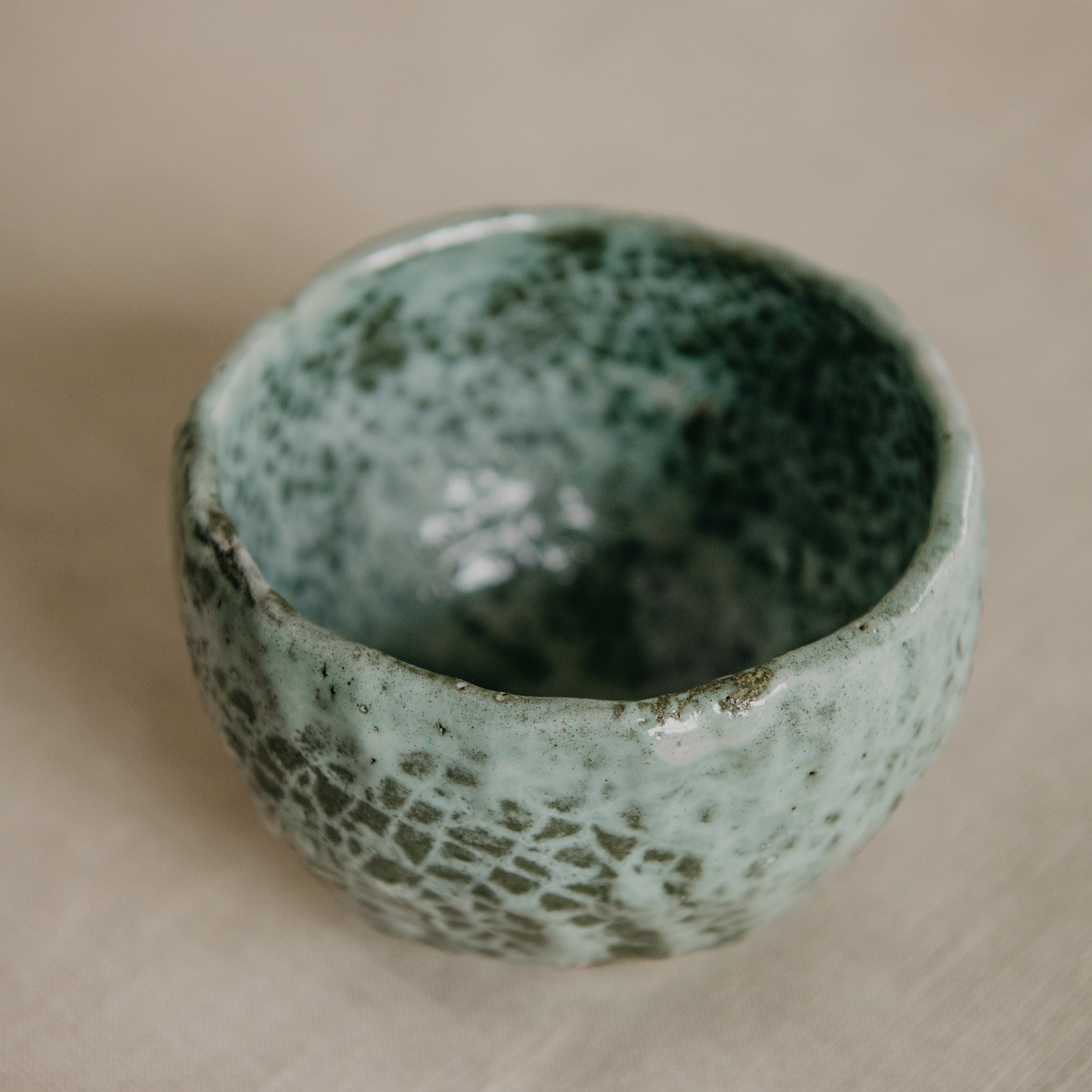 Green ceramic bowl on a beige fabric background