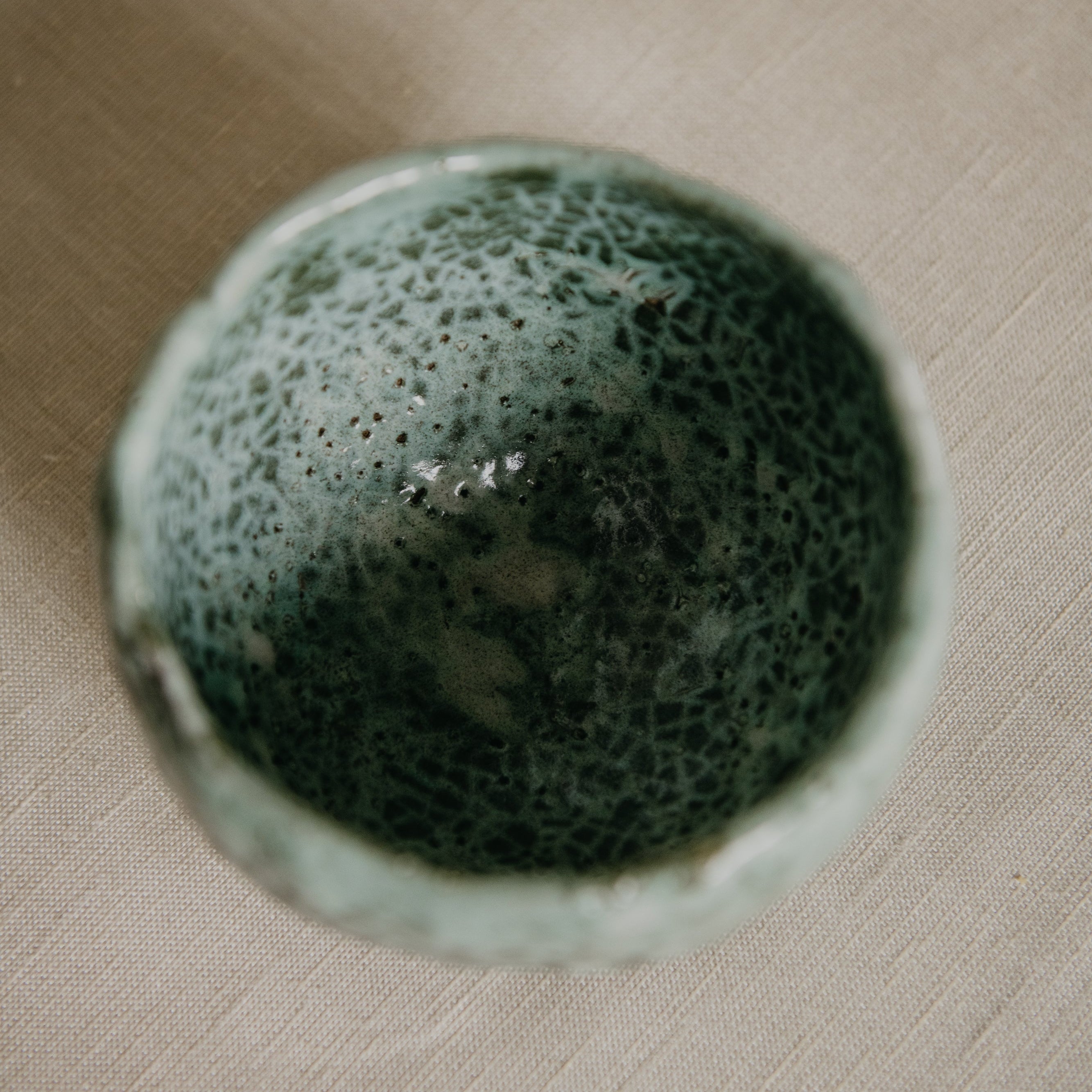 Green ceramic bowl on a beige surface