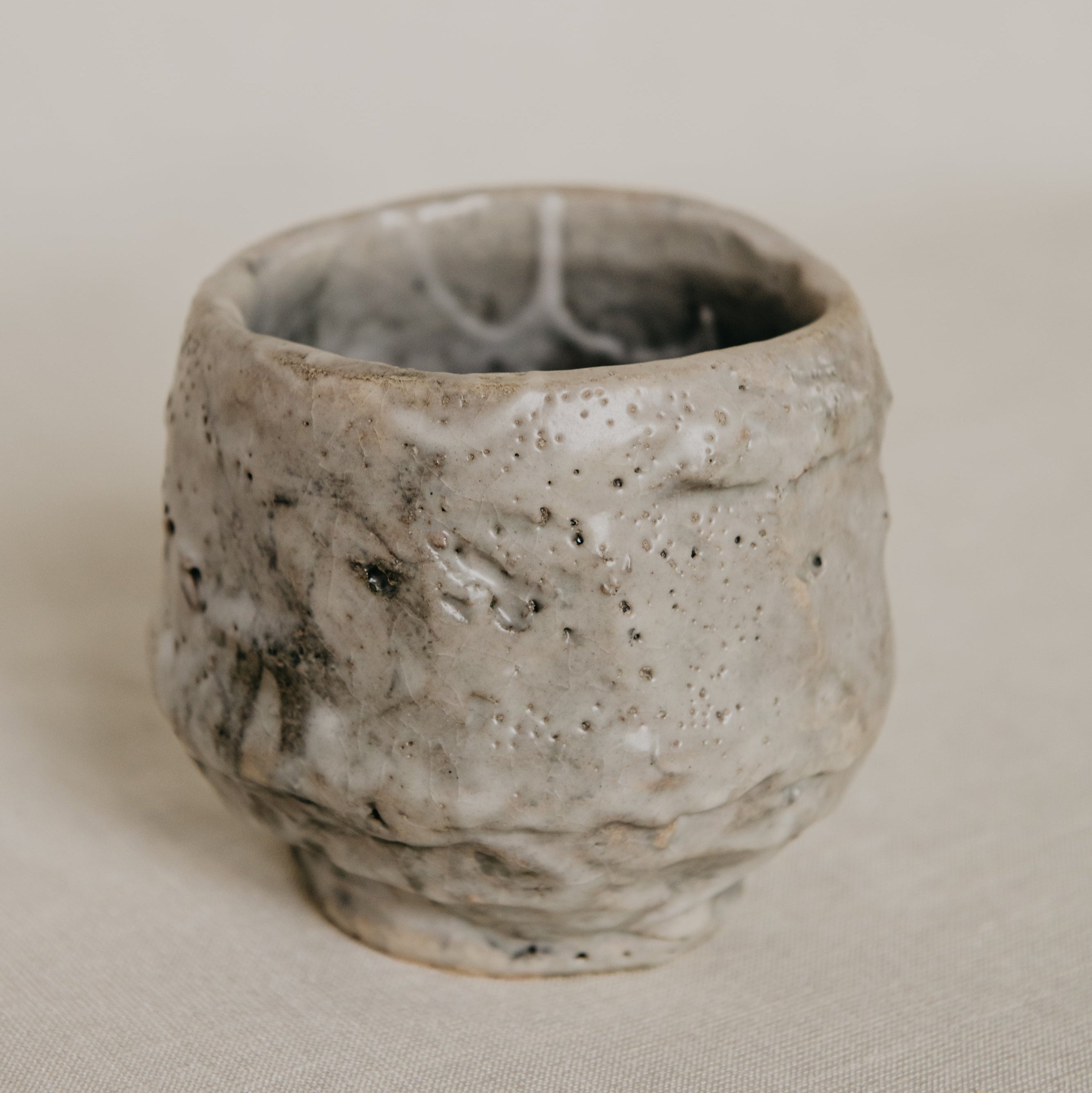 Handmade ceramic cup with textured surface on a neutral background