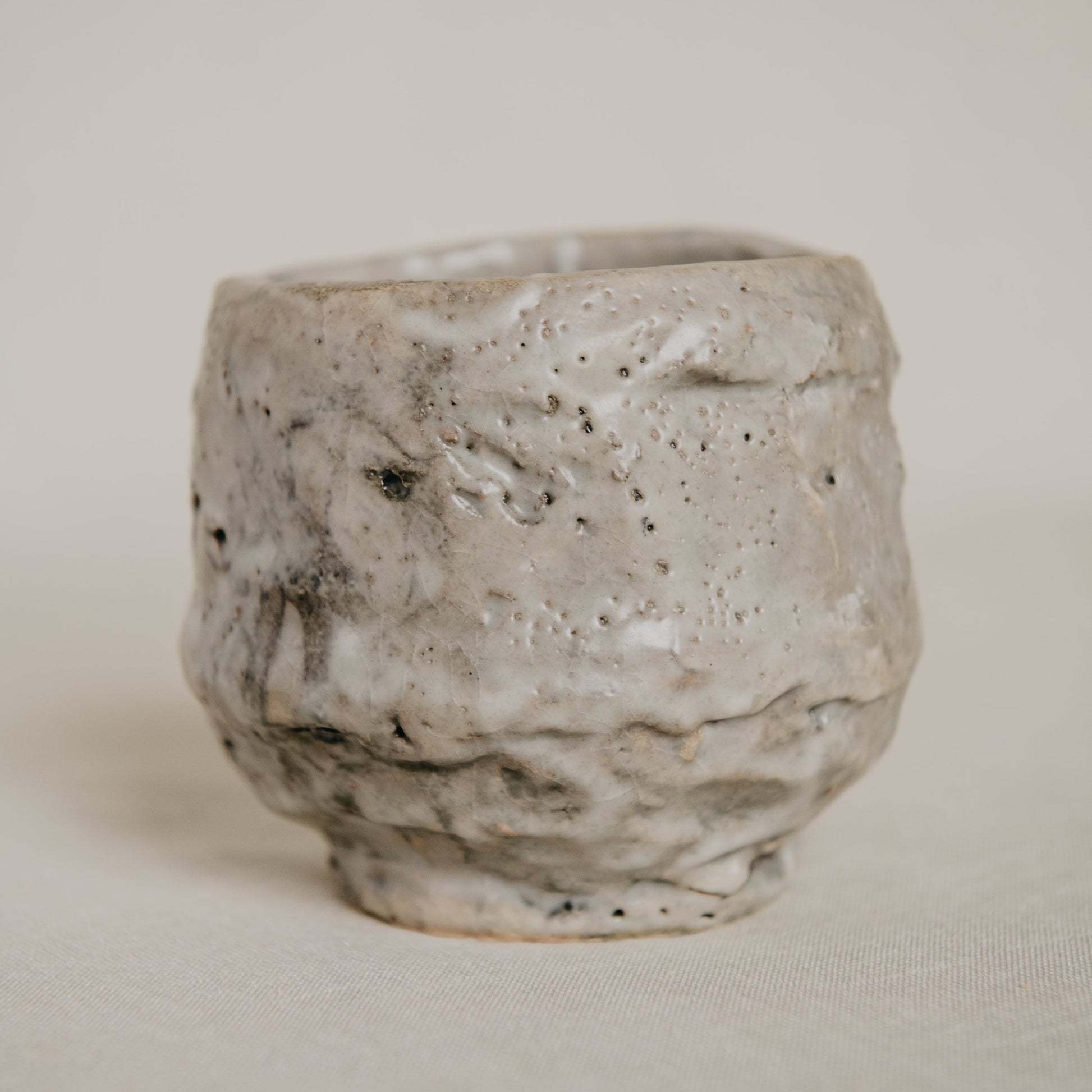 Handmade ceramic cup with textured surface on a plain background