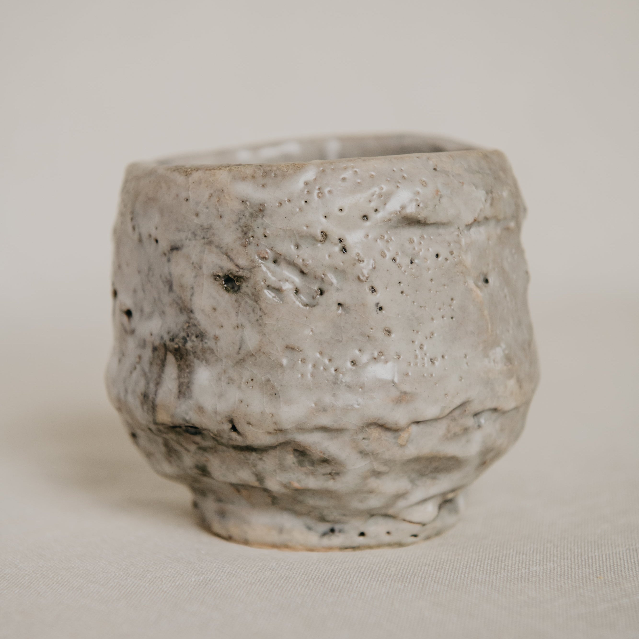 Handmade ceramic cup with textured surface on a plain background