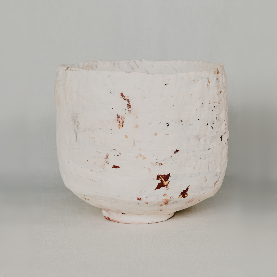 White ceramic pot with brown speckles on a light gray background