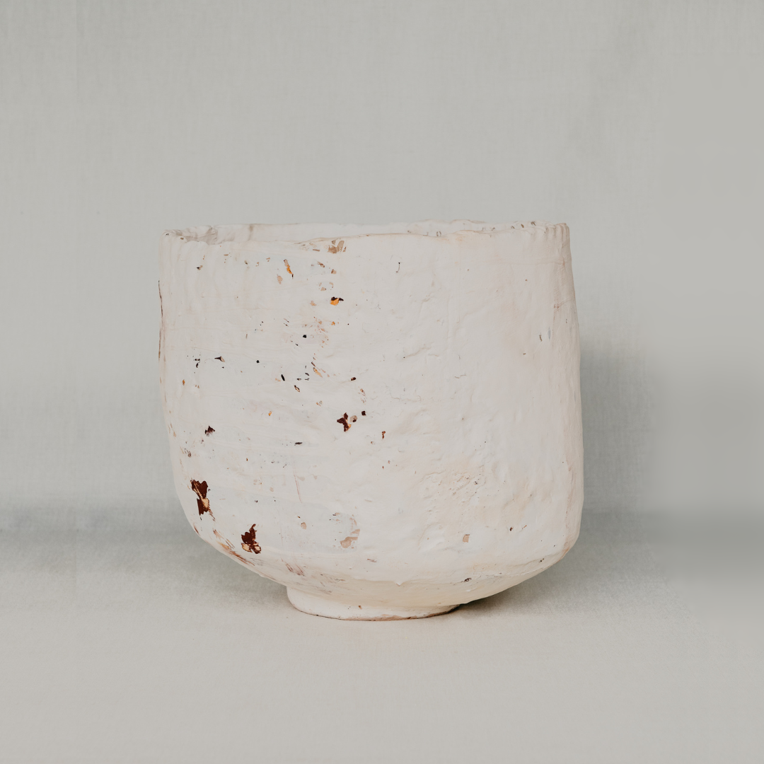 White ceramic cup with brown specks on a light gray background