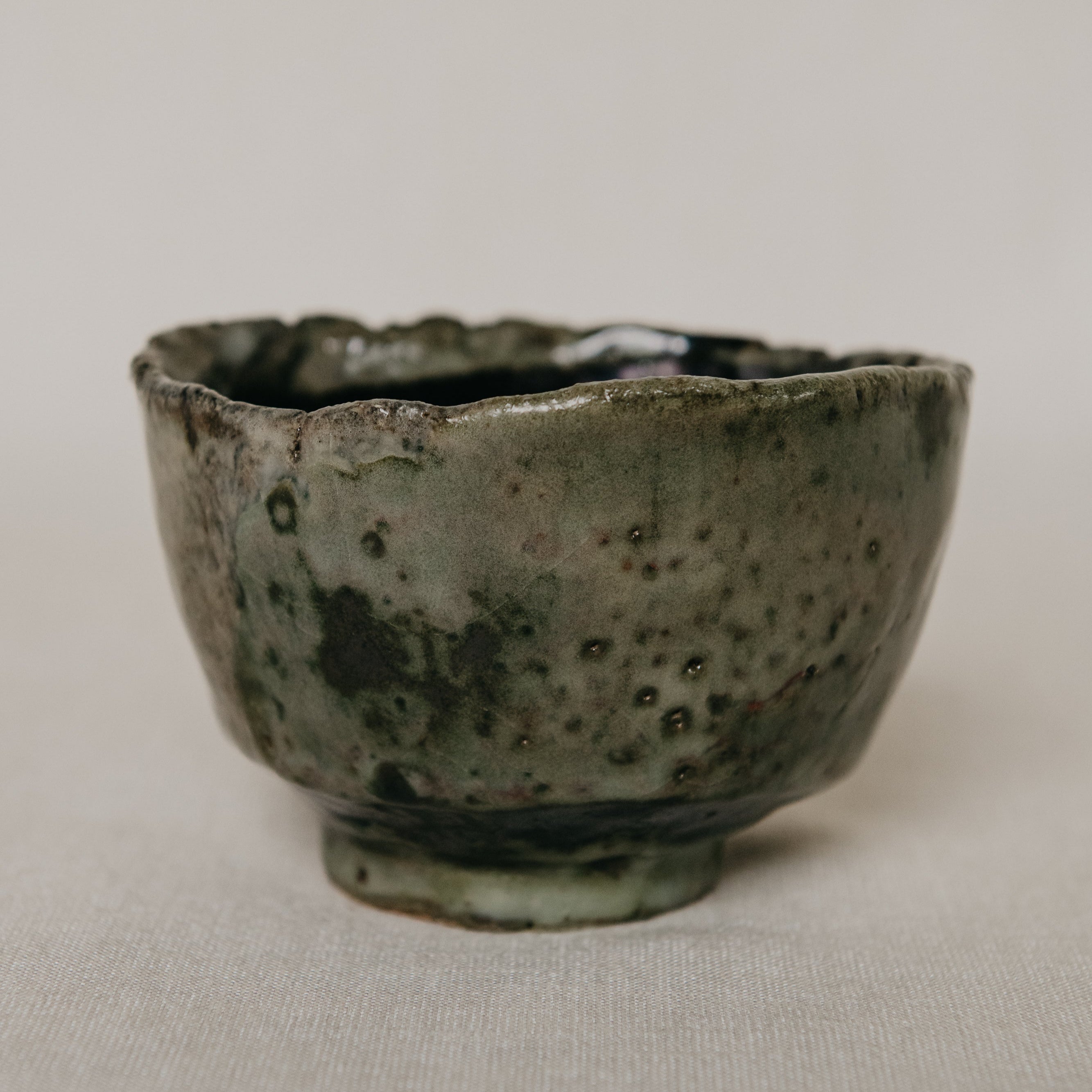 Green ceramic cup with speckled texture on a light gray background