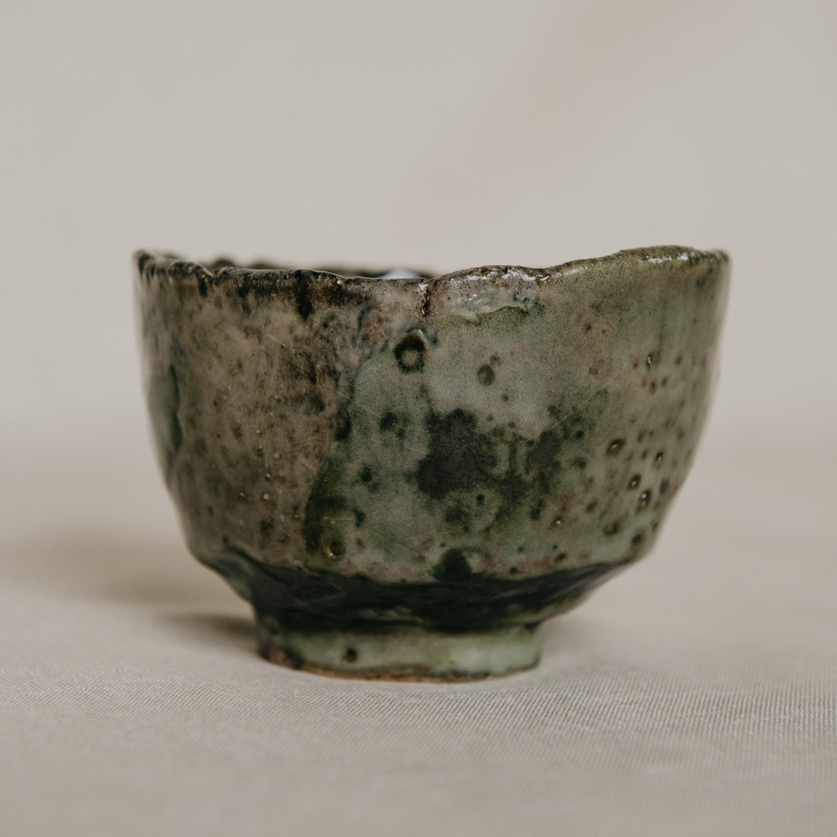 Small ceramic cup with a textured surface on a plain background