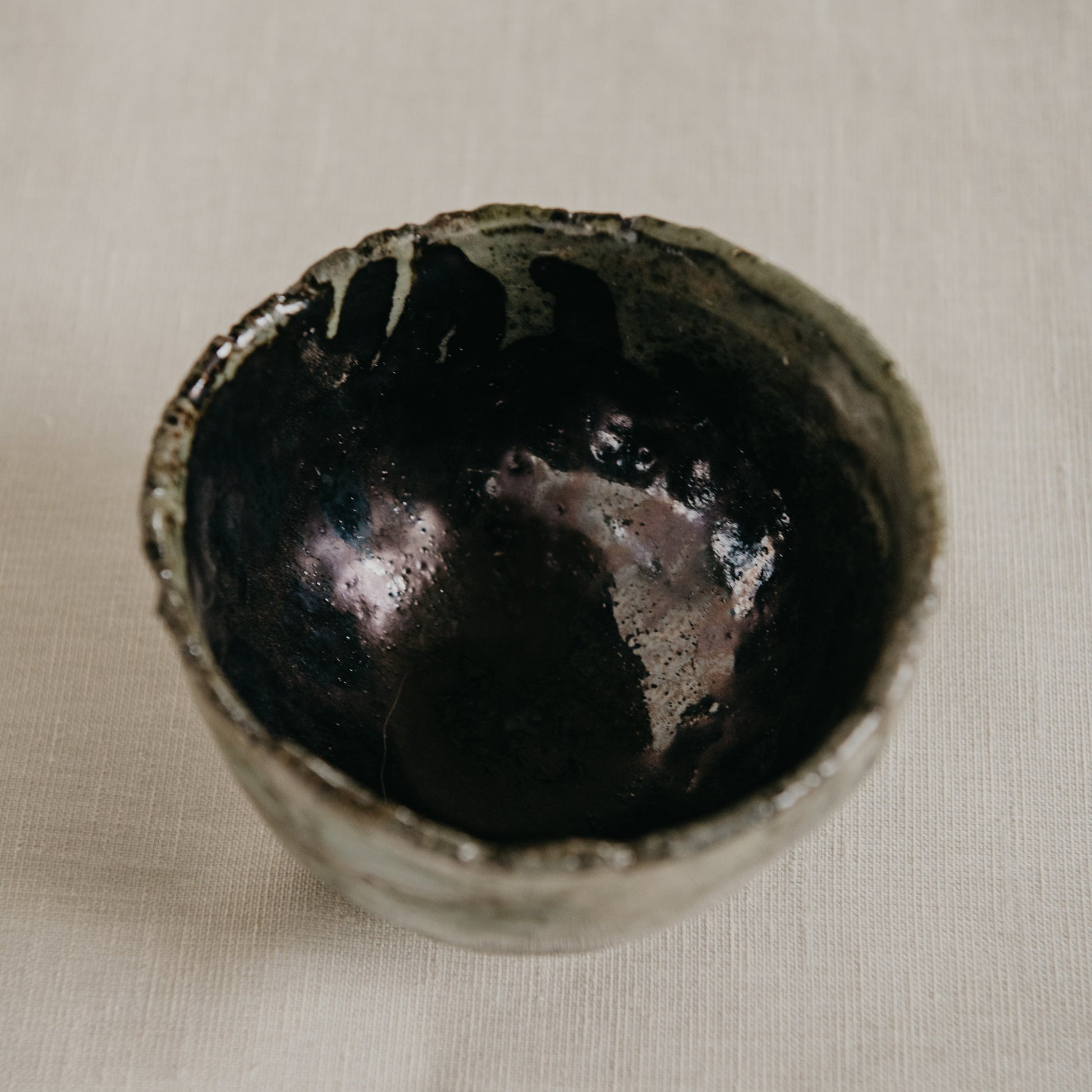 Black ceramic bowl on a beige fabric background