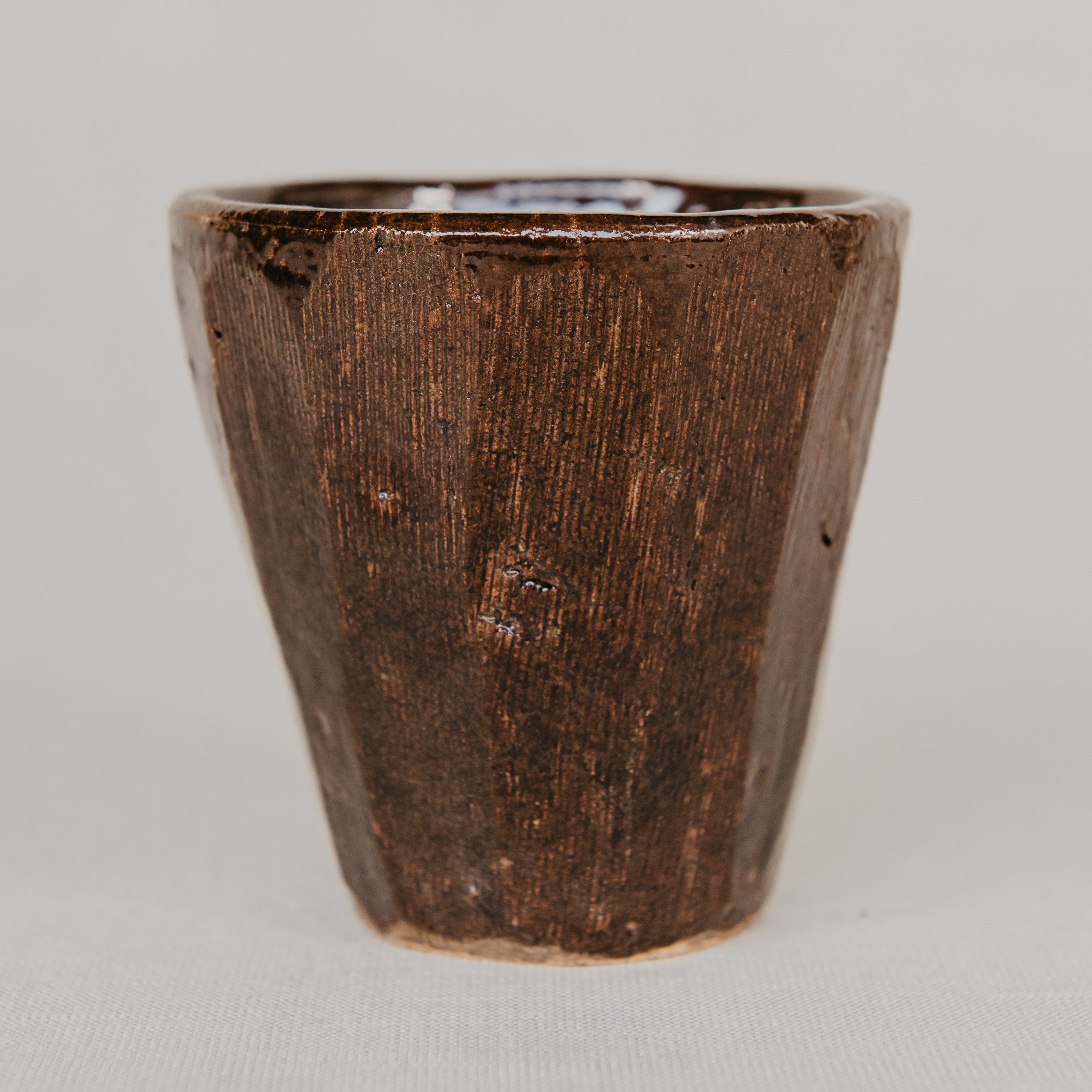 Brown ceramic cup on a light gray background