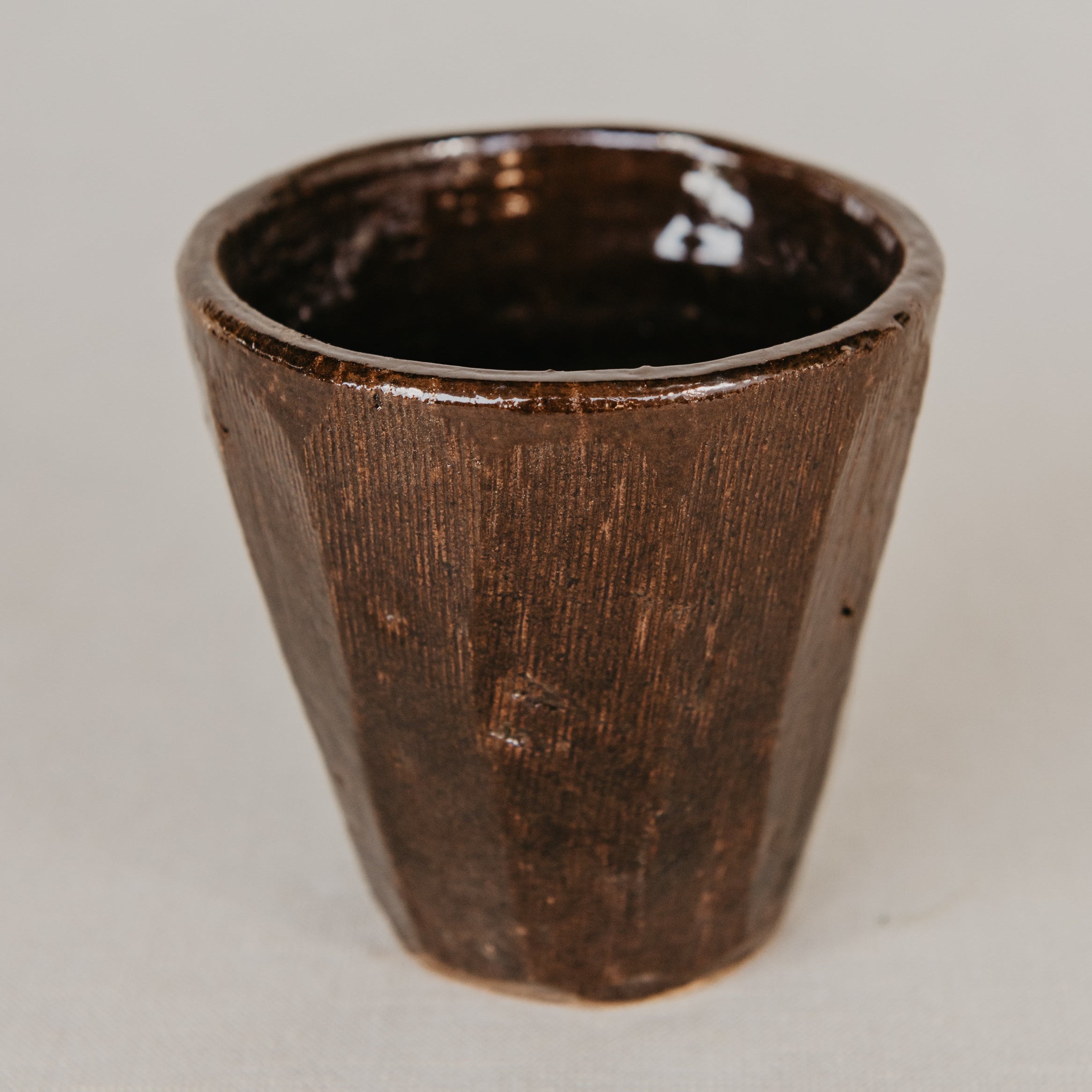 Brown ceramic cup on a light gray background