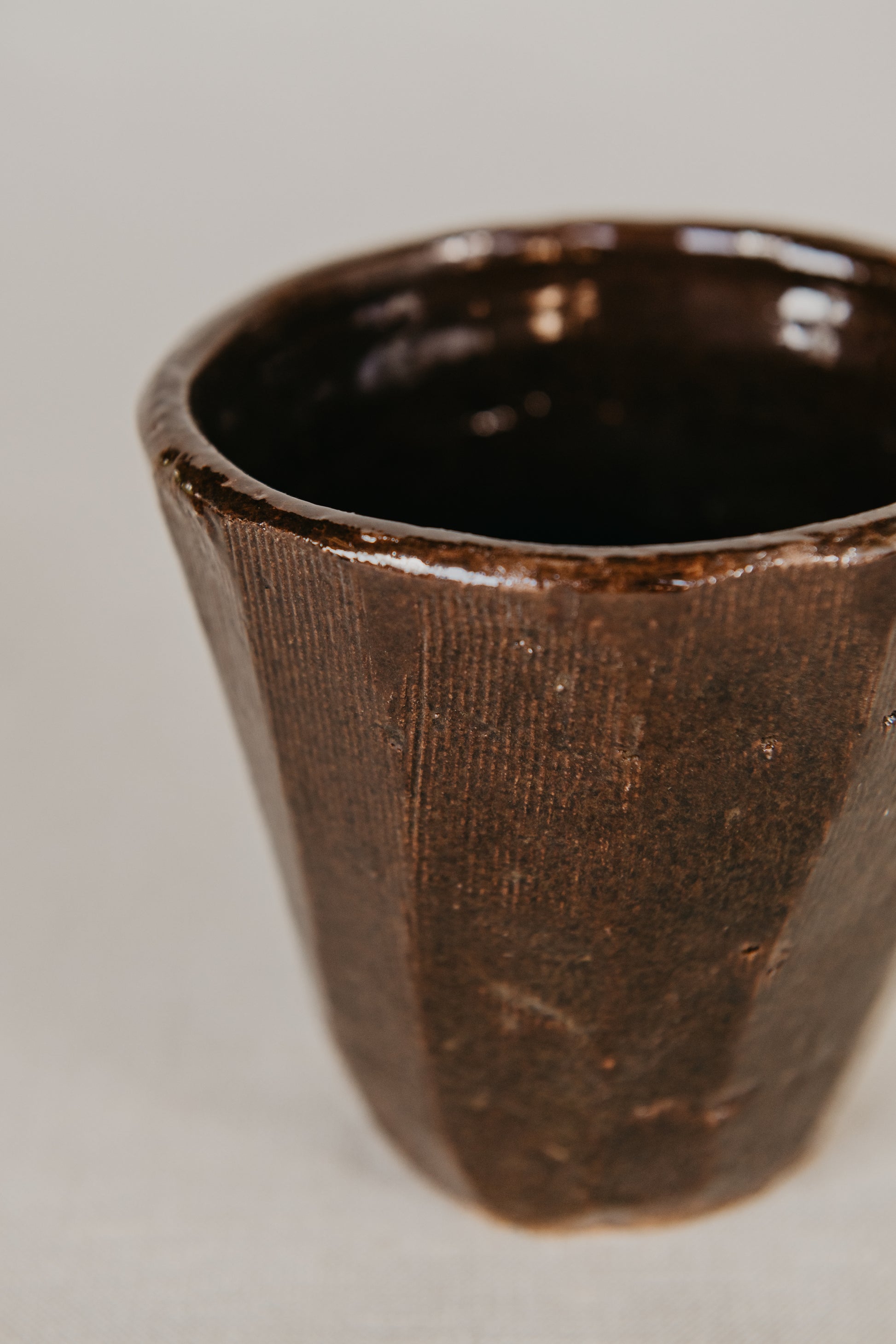 Close-up of a brown ceramic cup on a light gray background