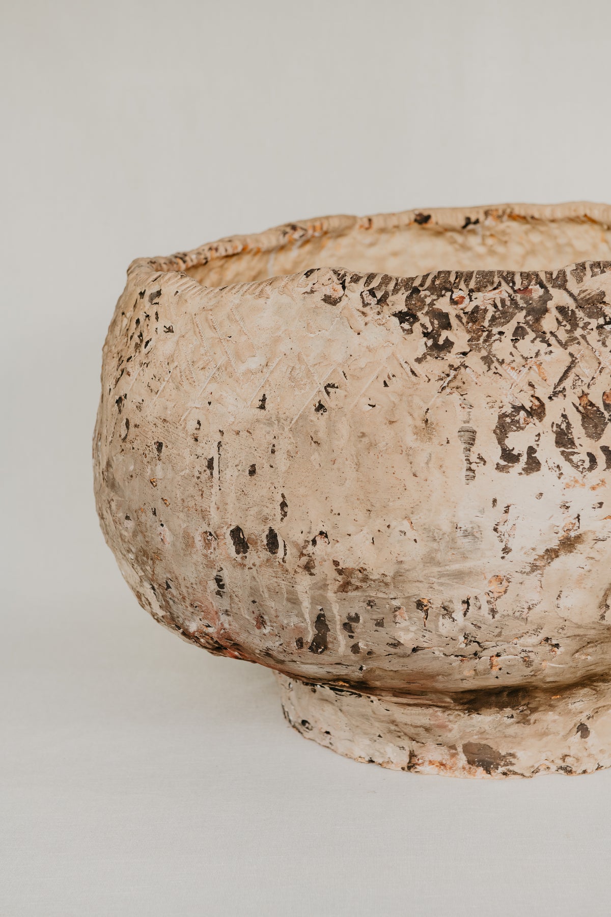 Ancient ceramic bowl with textured surface on a plain background